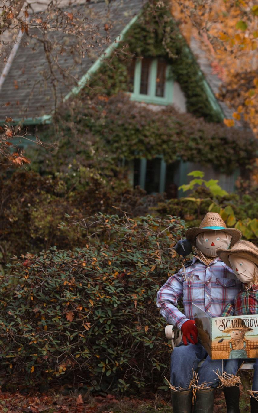 Adult and child scarecrow cuddled on a bench reading a story together.